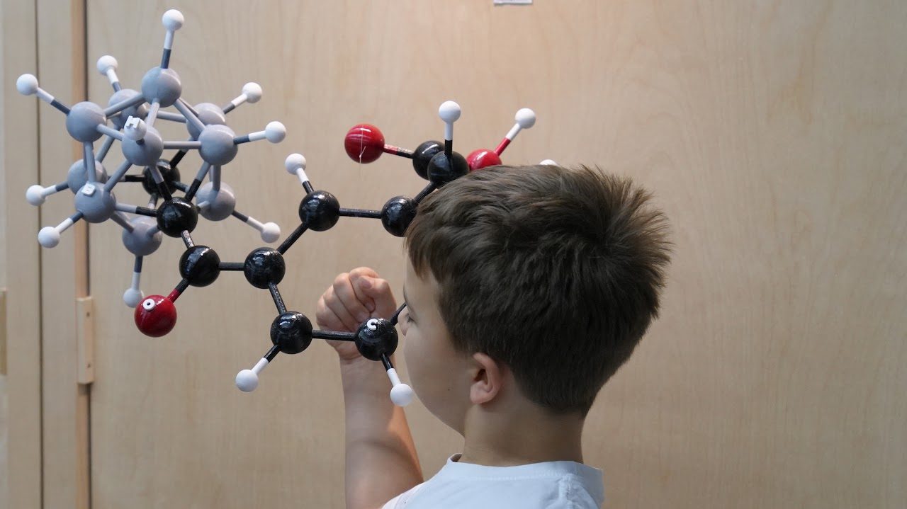 Dečak drži veliki model molekula